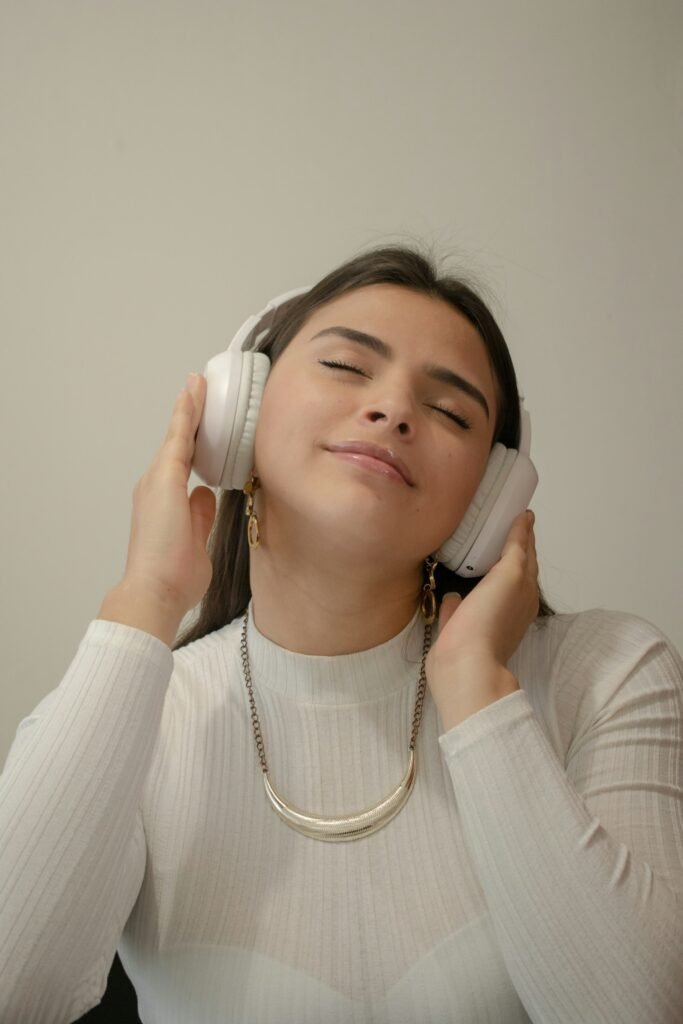 A woman wearing white headphones with eyes closed